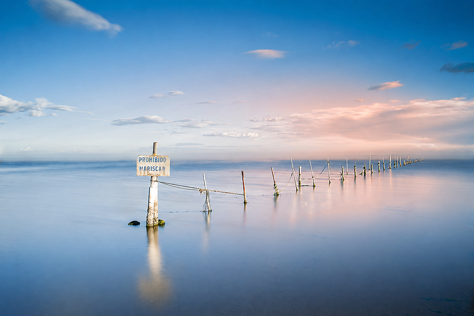 Coastal sign submerged in still water at dusk